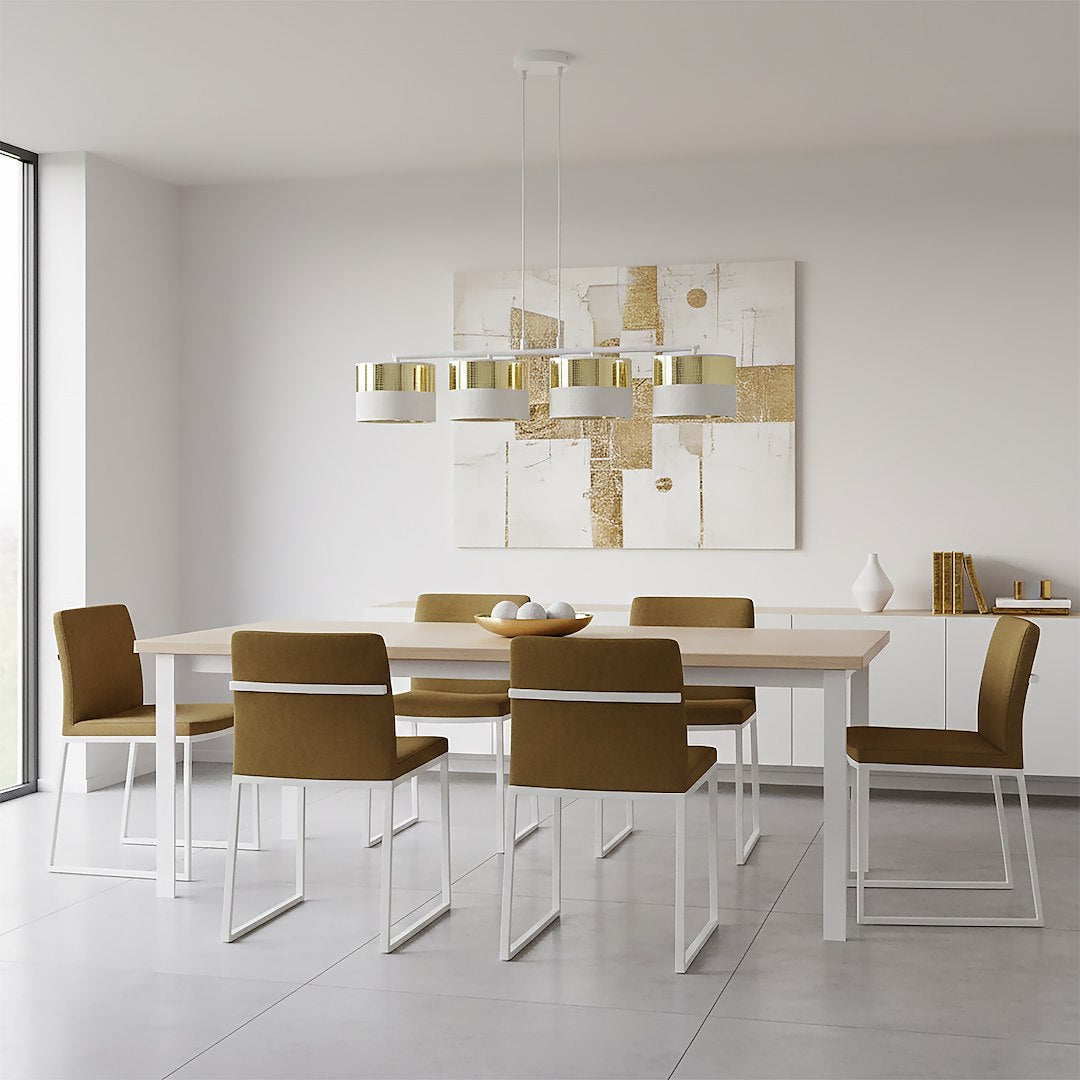 Pièce blanche avec chaises beige, suspension dorée au-dessus de la table à manger