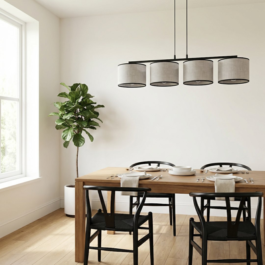 Luminaire suspendu au-dessus d'une table à manger en bois, chaises noires et plante verte