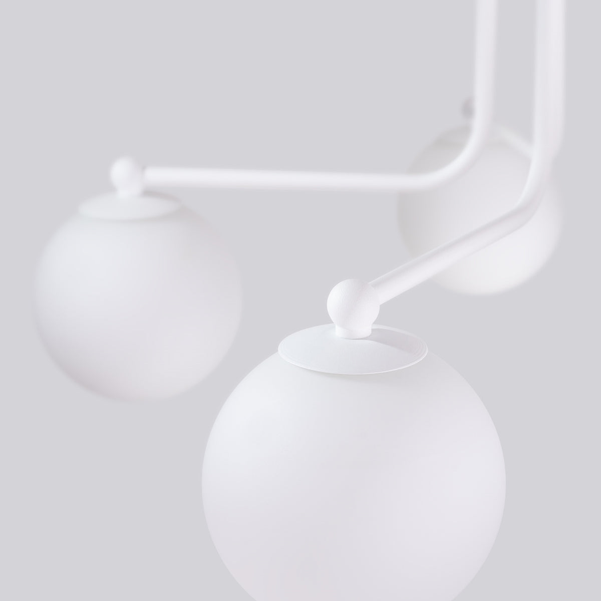 Détail rapproché des globes éteints, armature blanche et attaches sphériques.
