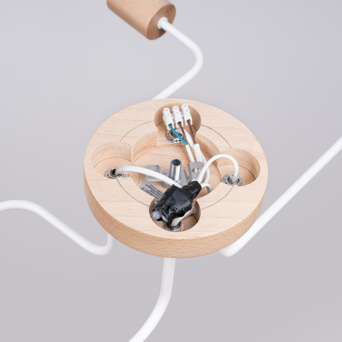 Détail du socle rond en bois, câblage et connexions électriques apparents.
