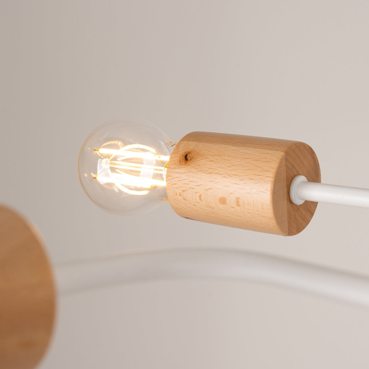 Gros plan d'une douille en bois avec ampoule allumée, câble blanc.