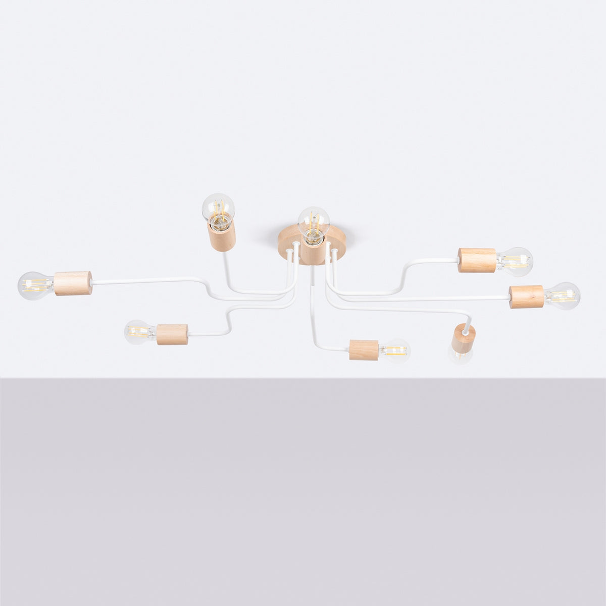 Luminaire entier présenté sur fond clair, bras blancs recourbés et douilles en bois.