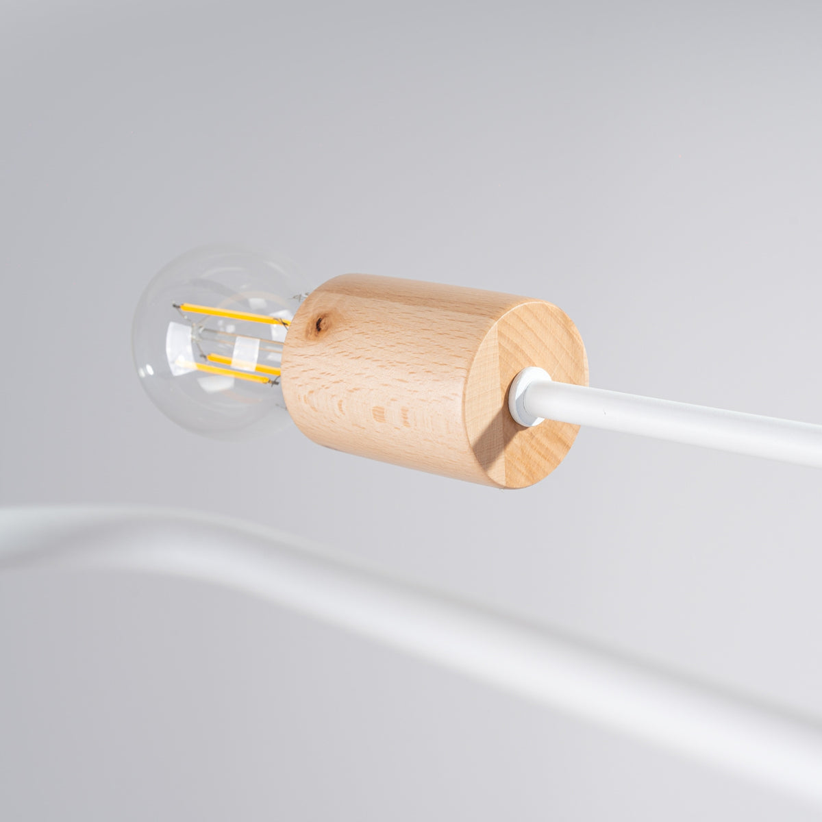 Détail d'une douille en bois et d'une ampoule éteinte, filament visible, câble blanc.
