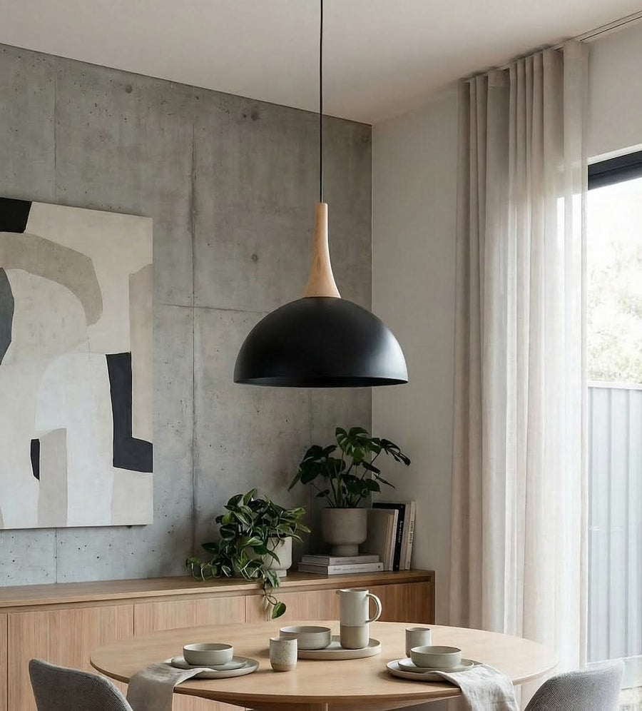 Suspension allumée dans un séjour béton avec table ronde et plante verte