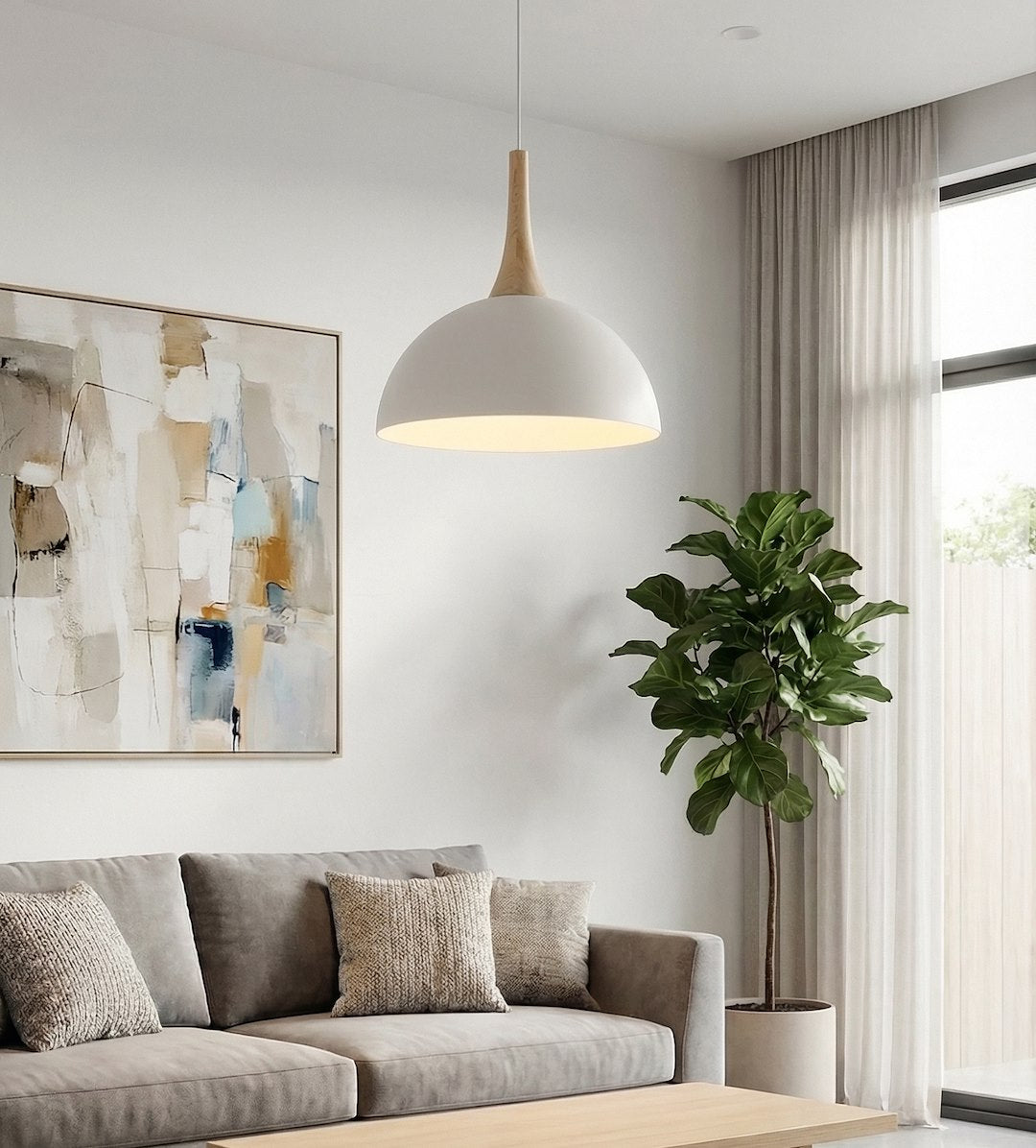 Suspension allumée dans un salon, devant un canapé gris et une grande plante verte.