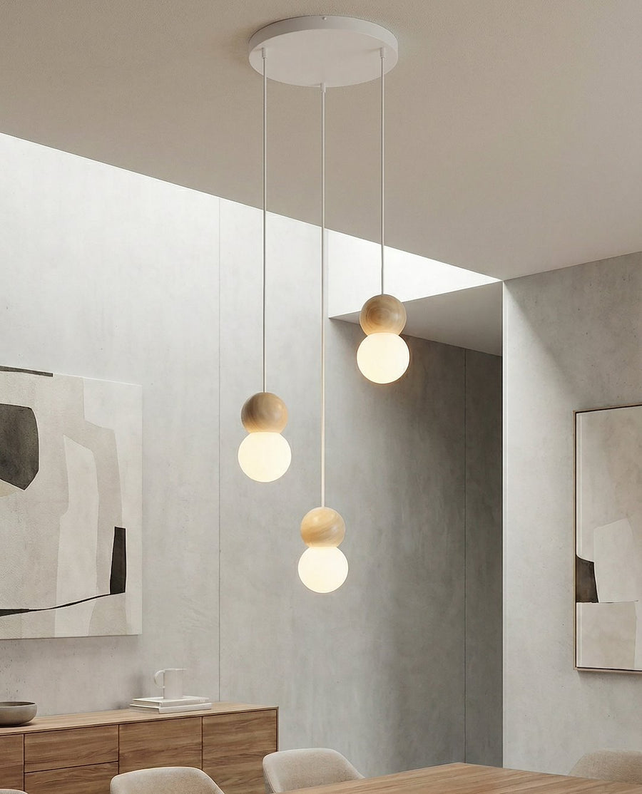 Ambiance salle à manger, table en bois et murs béton, trois globes suspendus