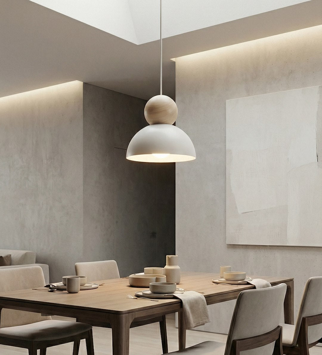 Salle à manger contemporaine, suspension allumée au-dessus d'une table en bois clair