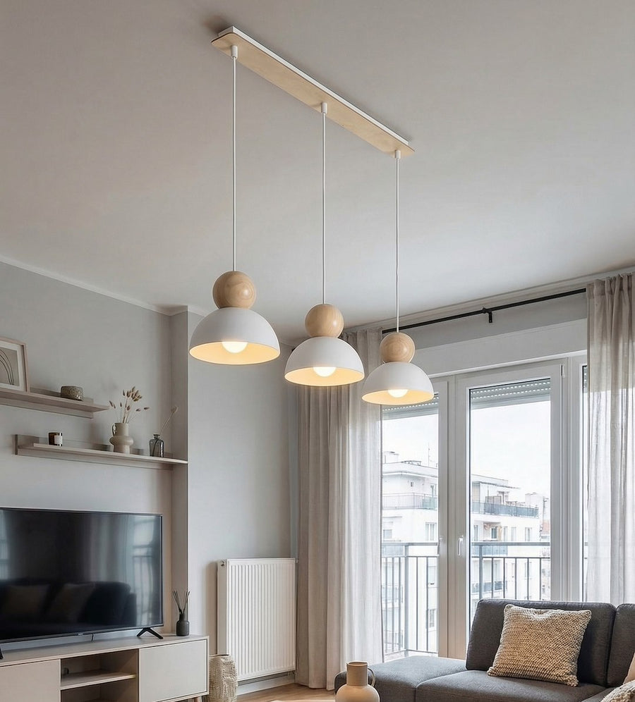 Suspension trois lumières éclairant un salon près d'une baie vitrée.