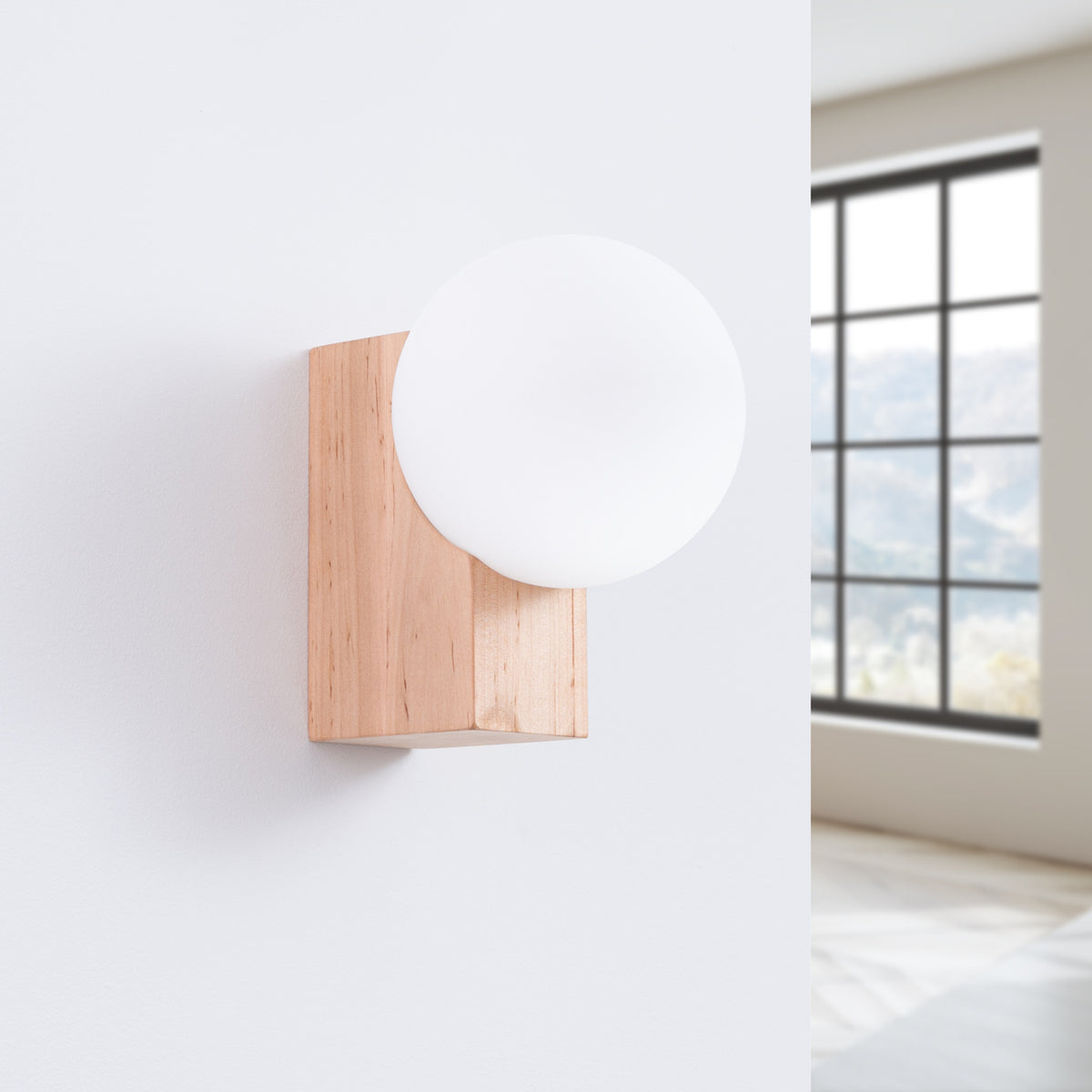 Applique fixée au mur blanc dans une pièce lumineuse, près d'une fenêtre à croisillons.