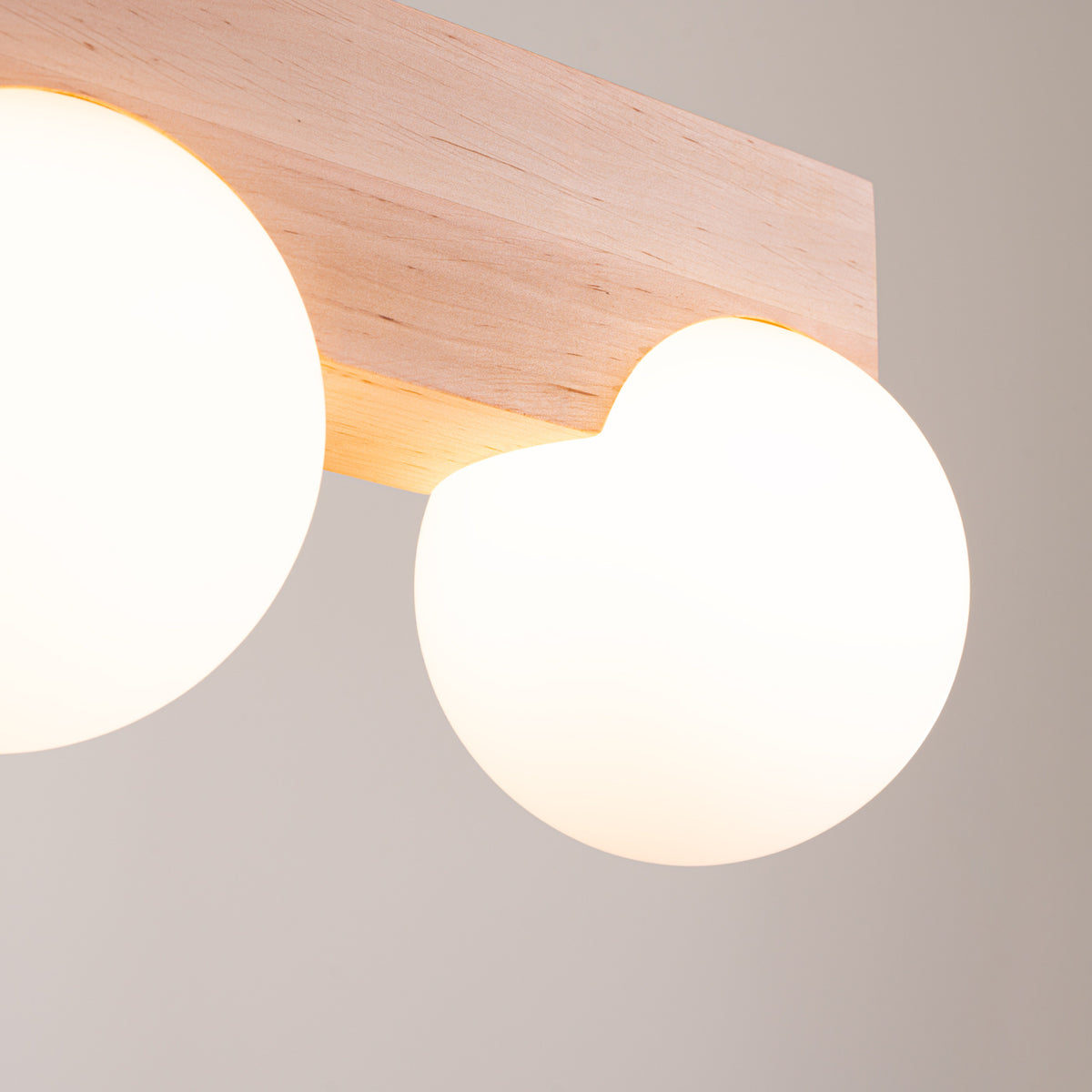 Détail rapproché des deux globes opalins et du socle en bois éclairé.