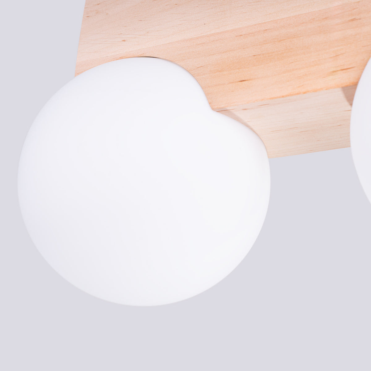 Gros plan sur un globe blanc et la découpe courbe du support en bois.