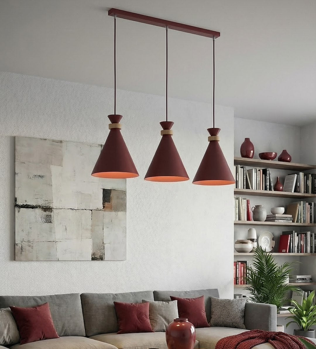 Trois cônes bordeaux suspendus devant un canapé gris dans un salon clair