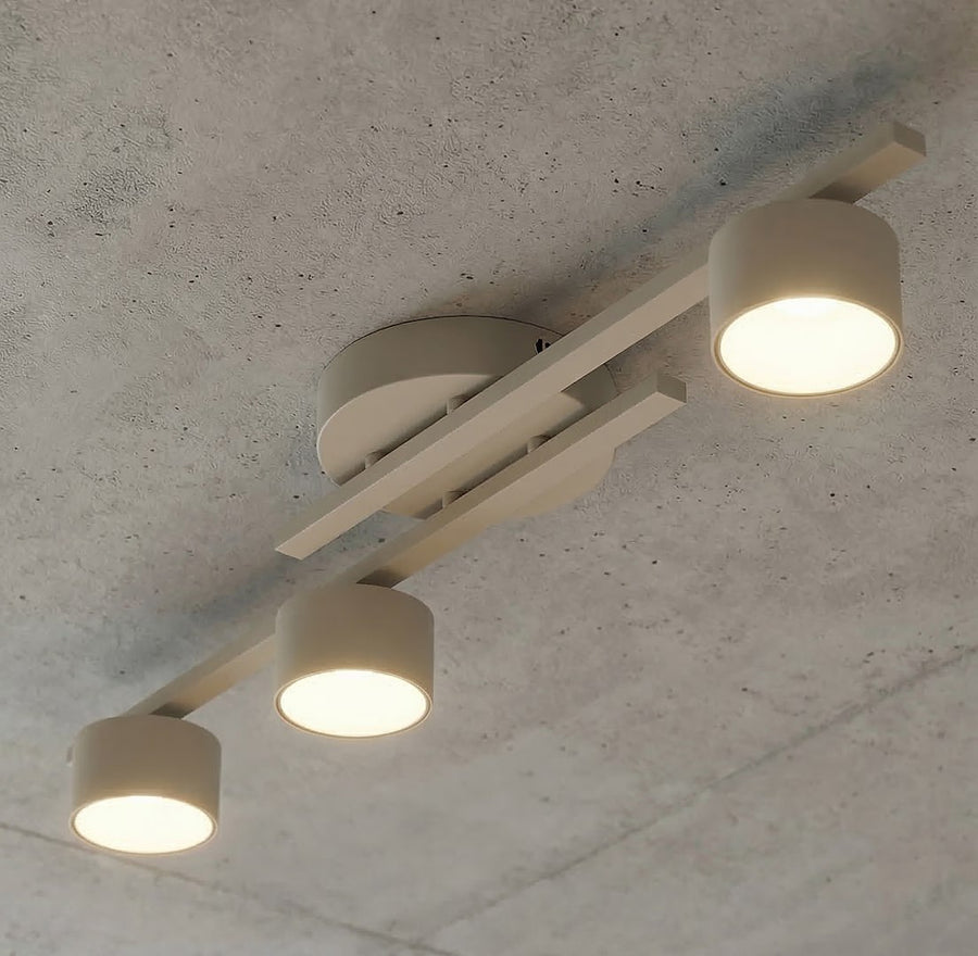 Détail rapproché des trois spots allumés fixés au plafond en béton brut