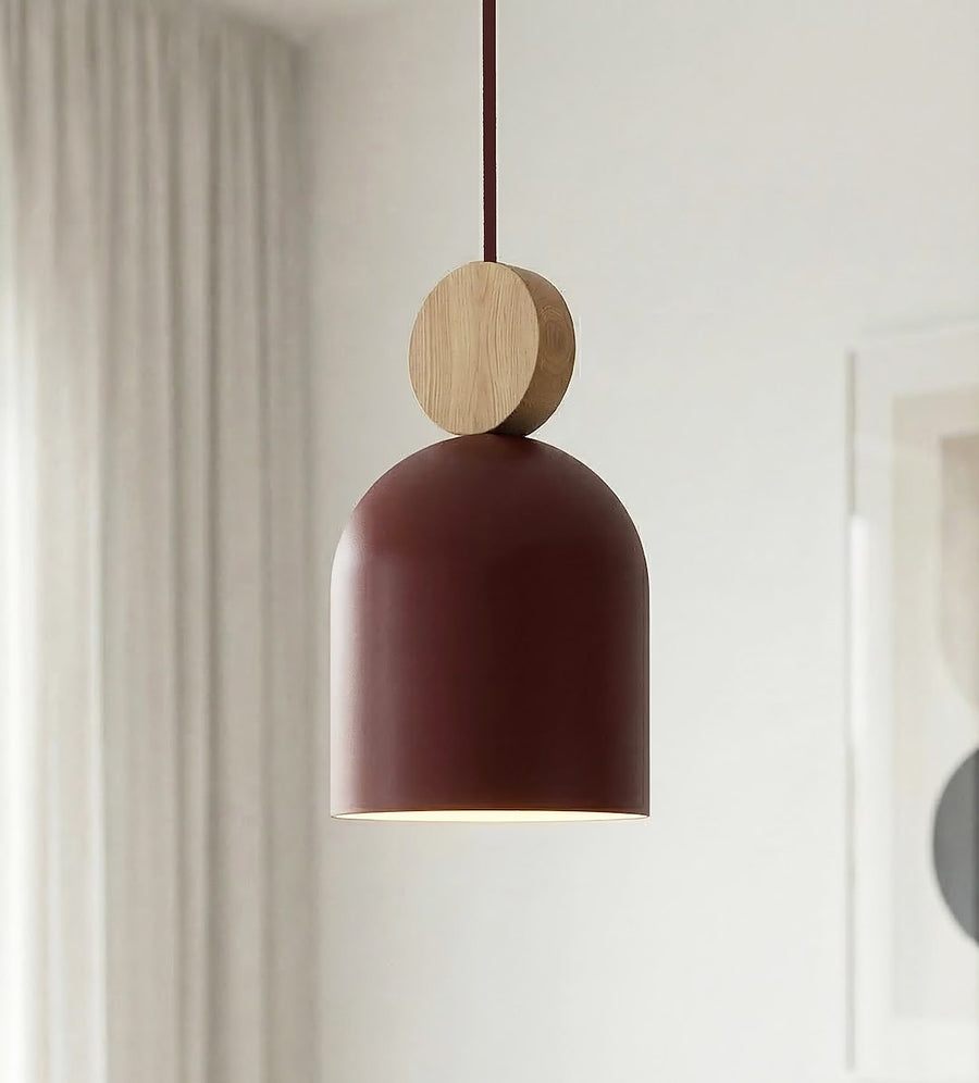 Détail rapproché d'une cloche bordeaux et de sa bille en bois clair.