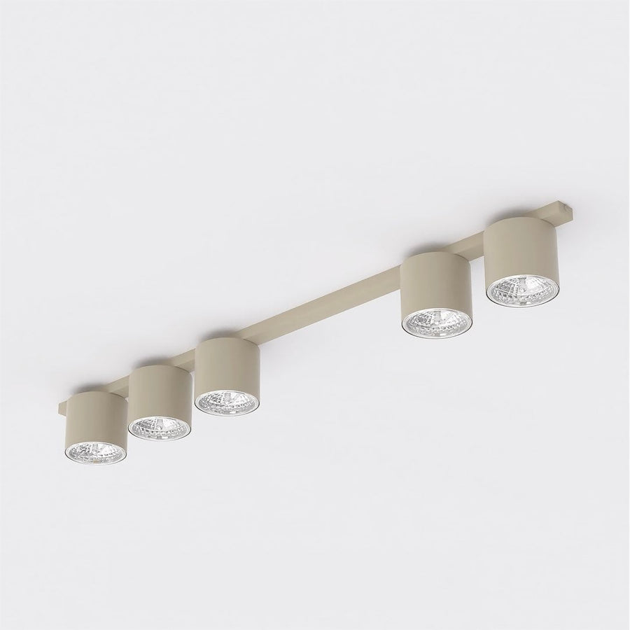 Plafonnier beige à cinq spots cylindriques orientables vu de trois quarts sur fond blanc