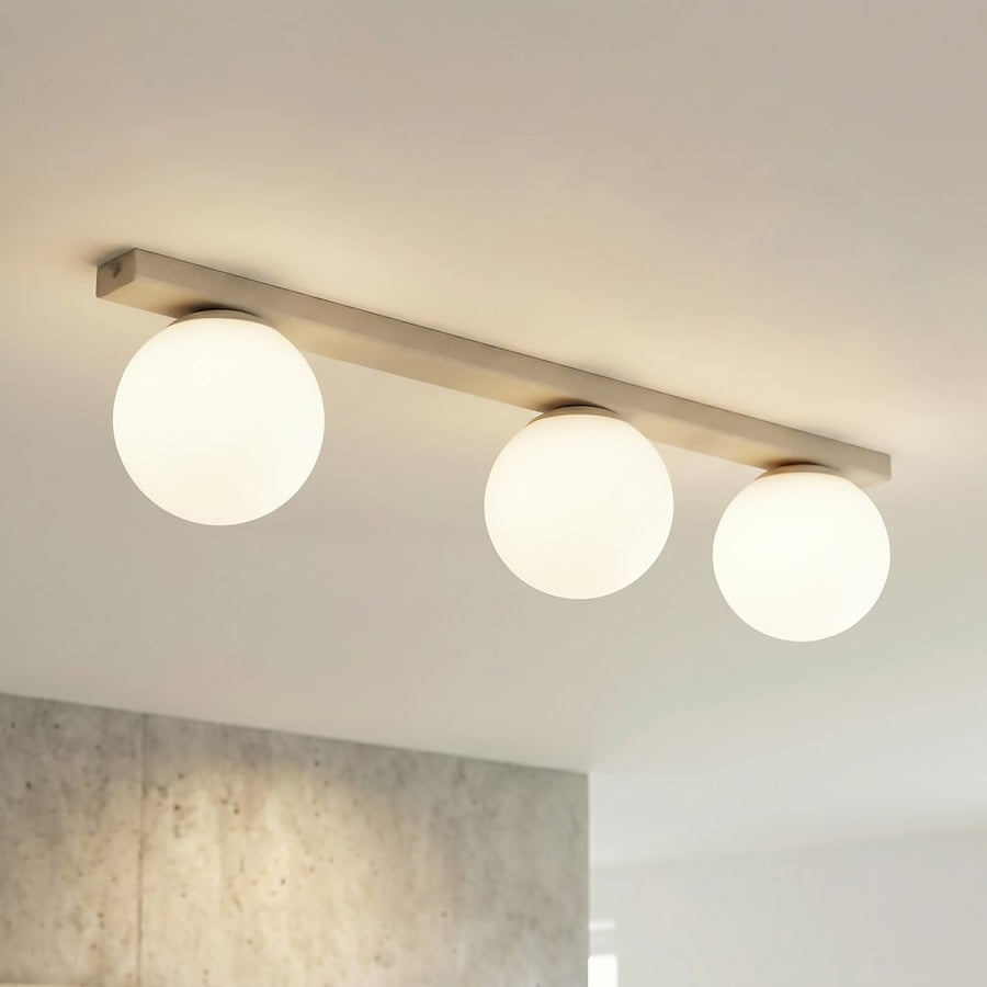 Gros plan du luminaire allumé, globes ivoire sous plafond clair.