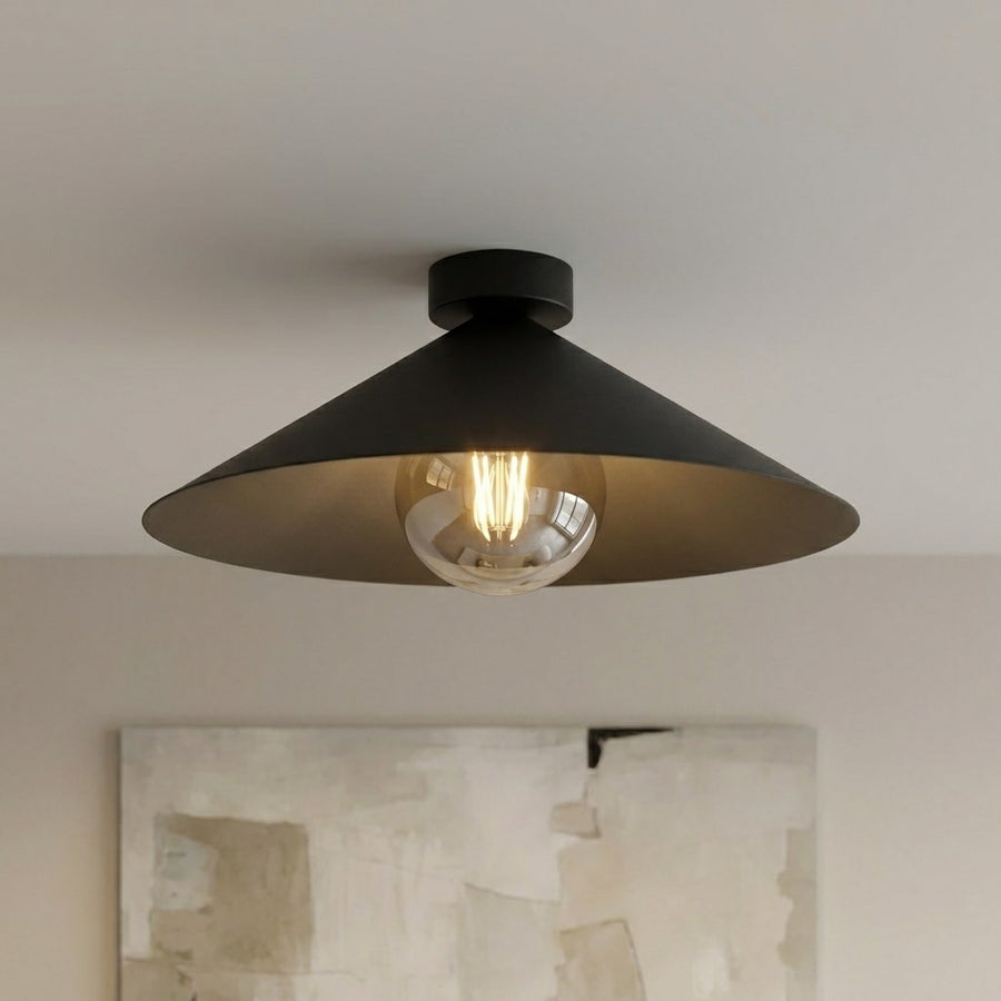 Détail du luminaire allumé, ampoule visible à travers le globe de verre