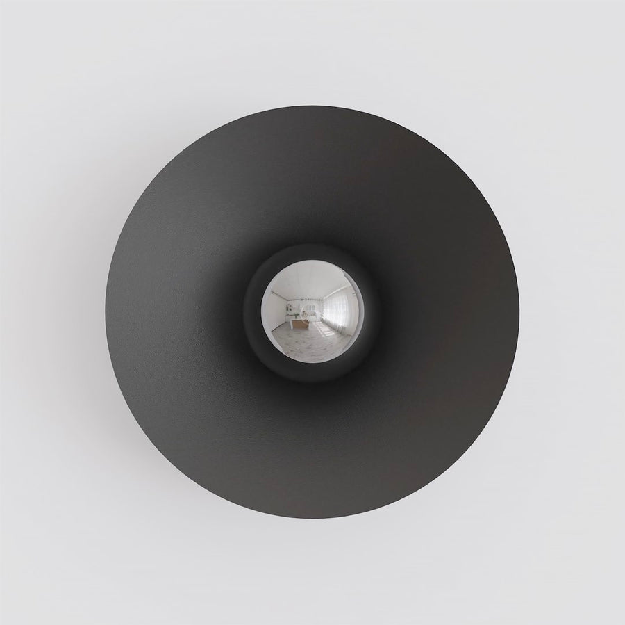 Vue de face sur fond blanc, disque noir et verre central réfléchissant une pièce.