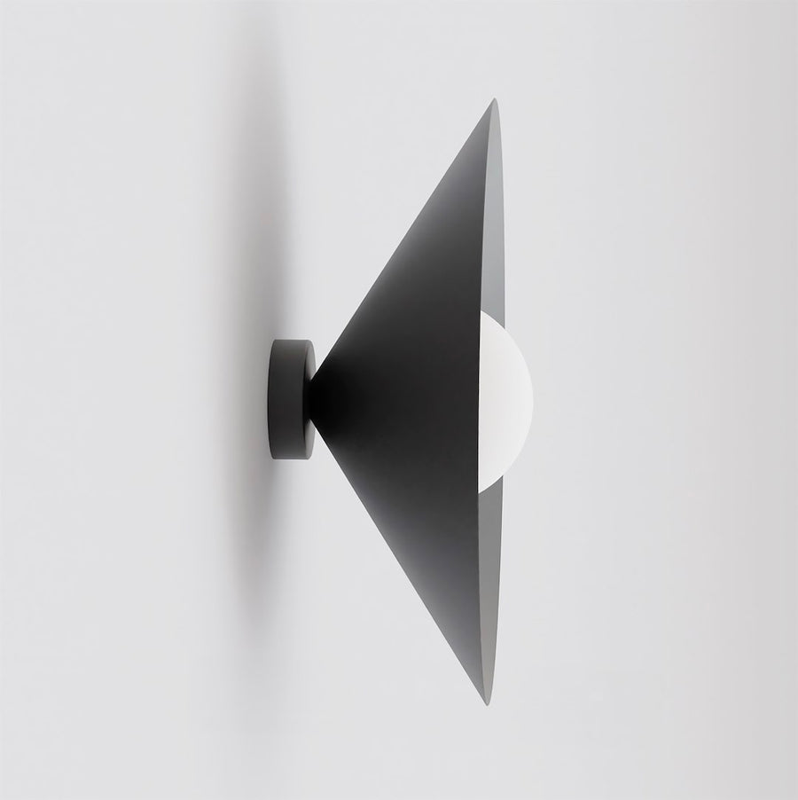 Vue de profil du cône noir et de la sphère blanche sur un mur clair