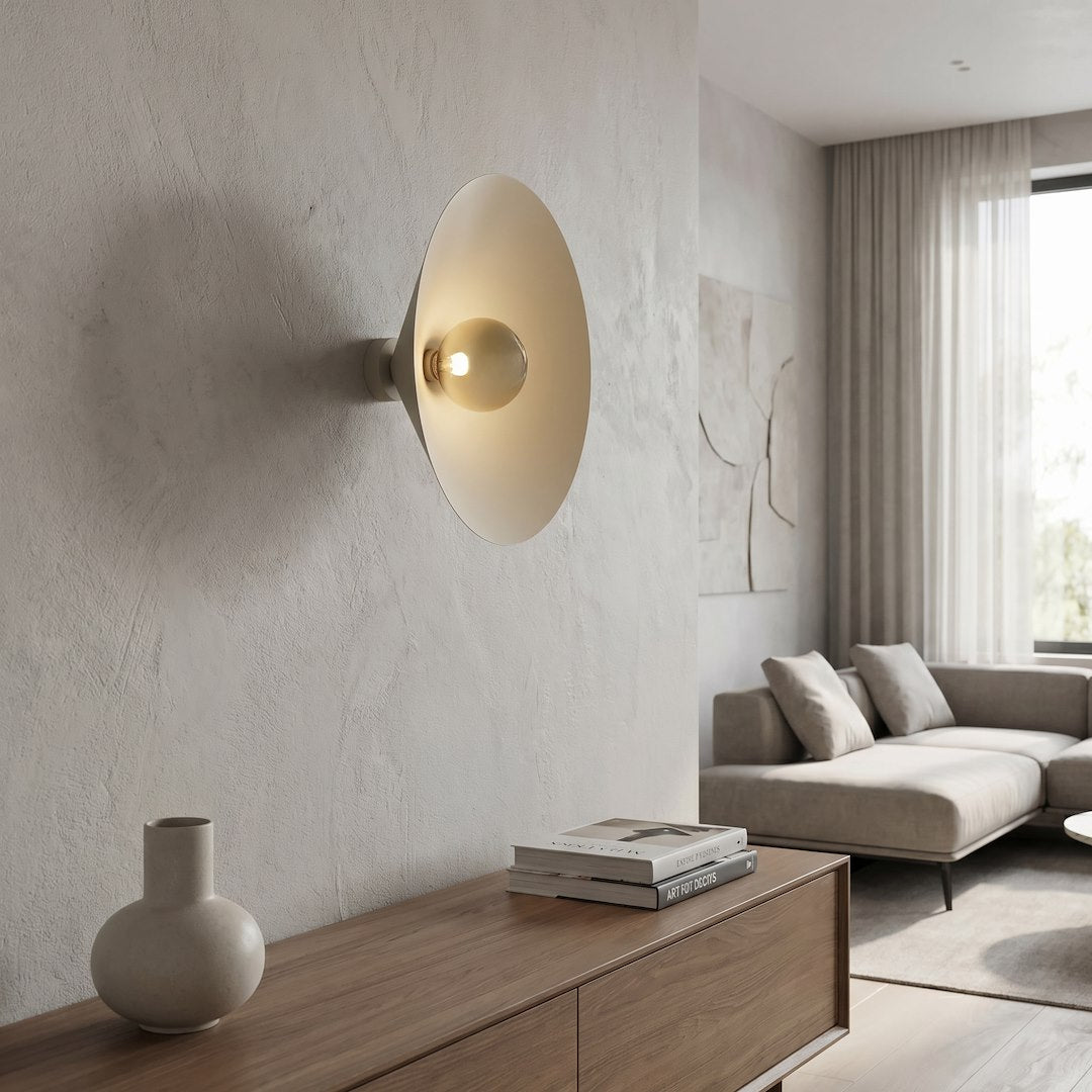 Mise en ambiance de l'applique allumée dans un salon beige avec canapé et crédence en bois.