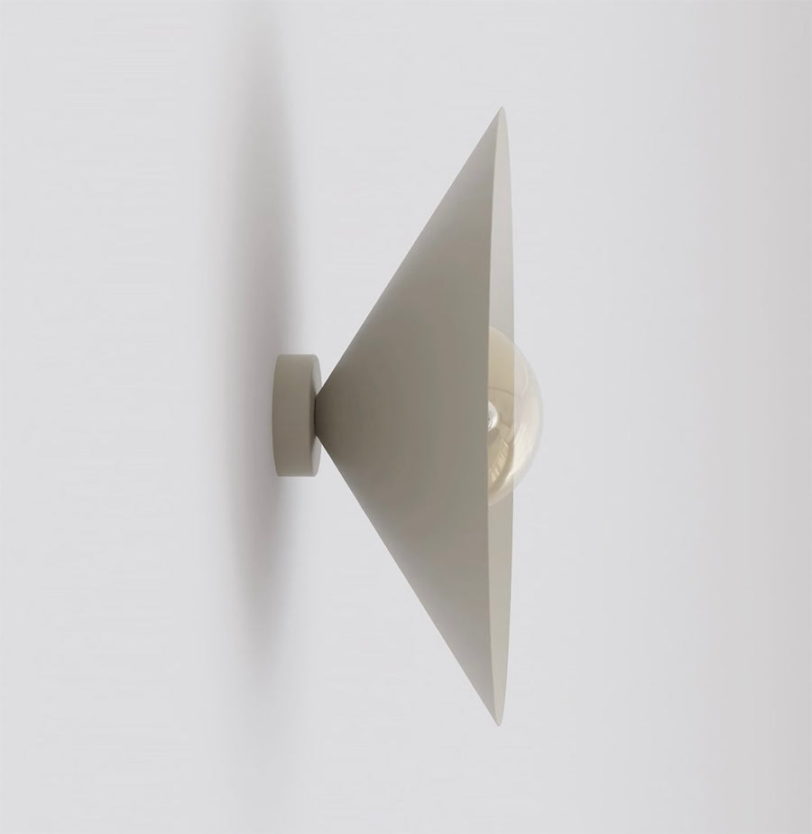 Vue de profil de l’applique beige, cône orienté vers le haut, ampoule ambrée visible.