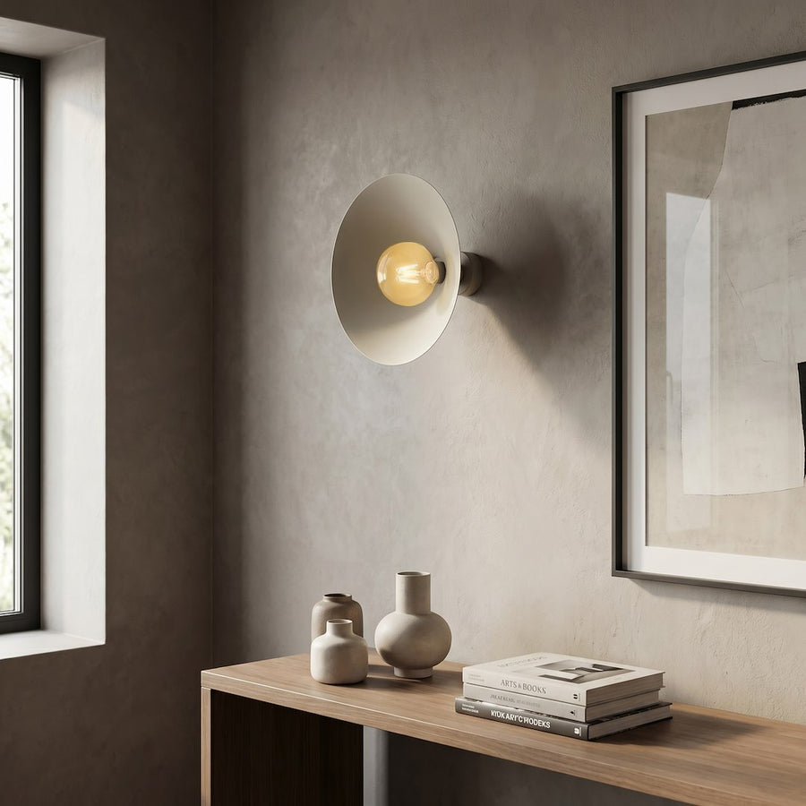 Mise en scène de l’applique beige allumée dans un intérieur minimaliste avec cadres.