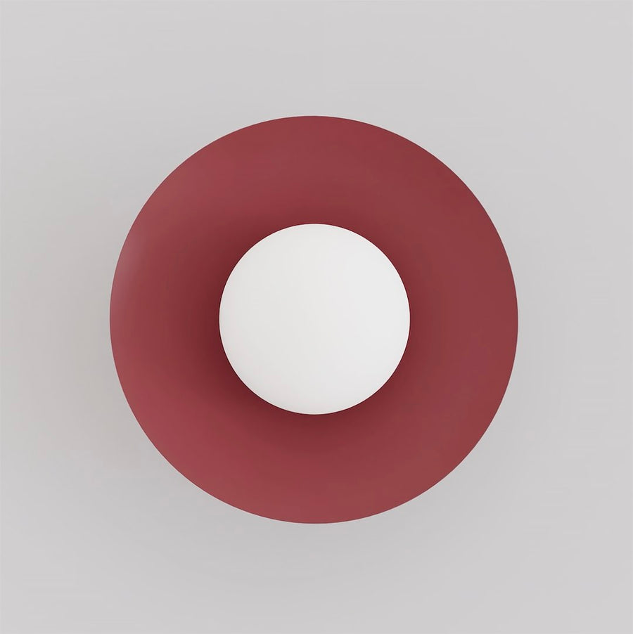 Vue de face de l'applique murale ronde bordeaux avec diffuseur sphérique blanc.
