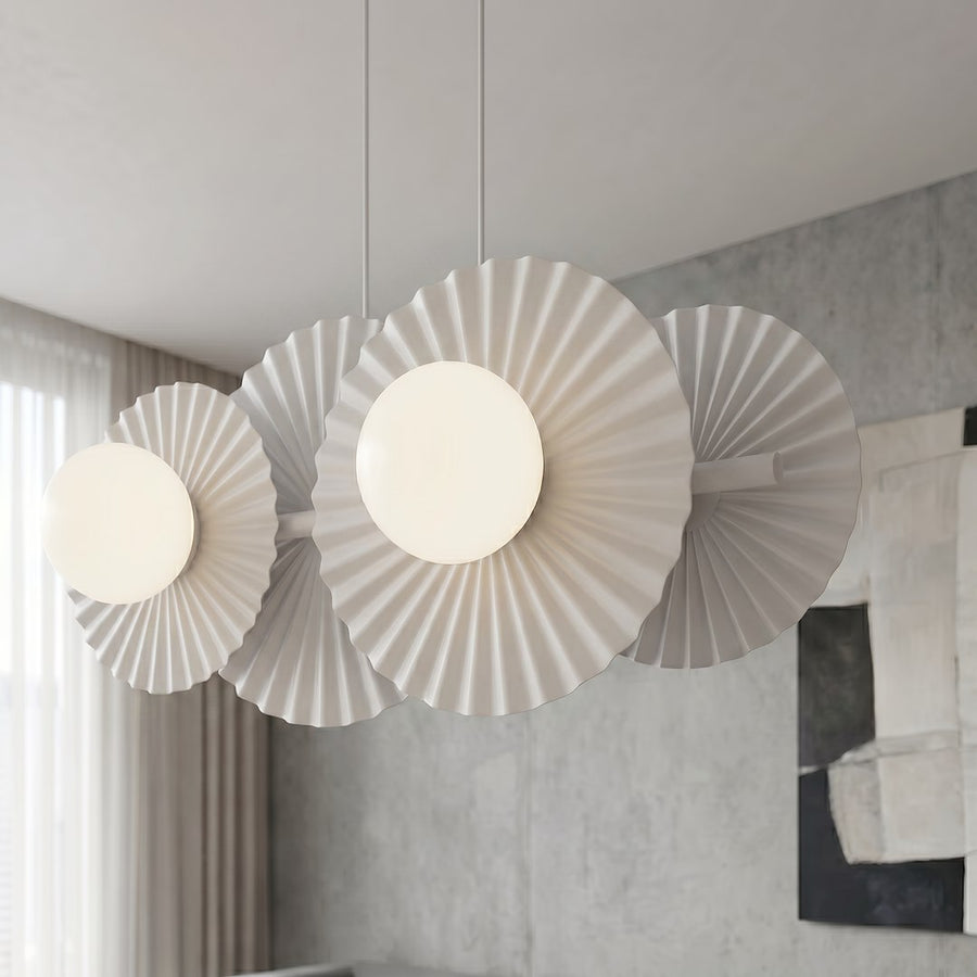 Gros plan sur les disques plissés et les globes opalins du luminaire allumé.