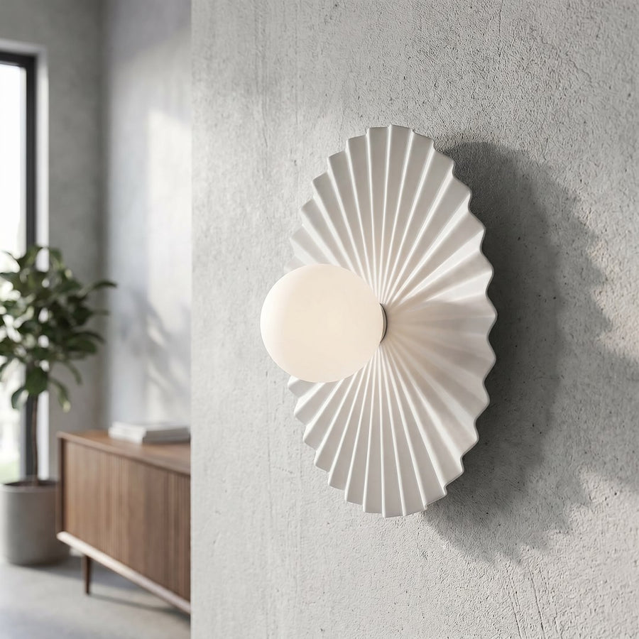 Gros plan de l’applique allumée sur un mur texturé, intérieur lumineux.