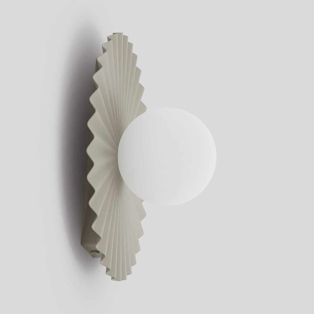 Vue de profil de l'applique murale montrant le globe en verre blanc et le plissé beige.