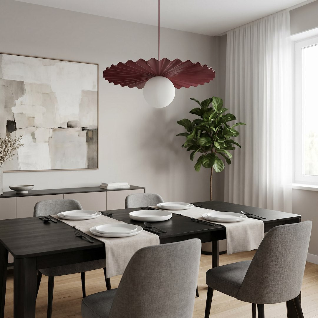 Luminaire suspendu bordeaux et blanc au-dessus d'une table noire dressée, intérieur moderne.