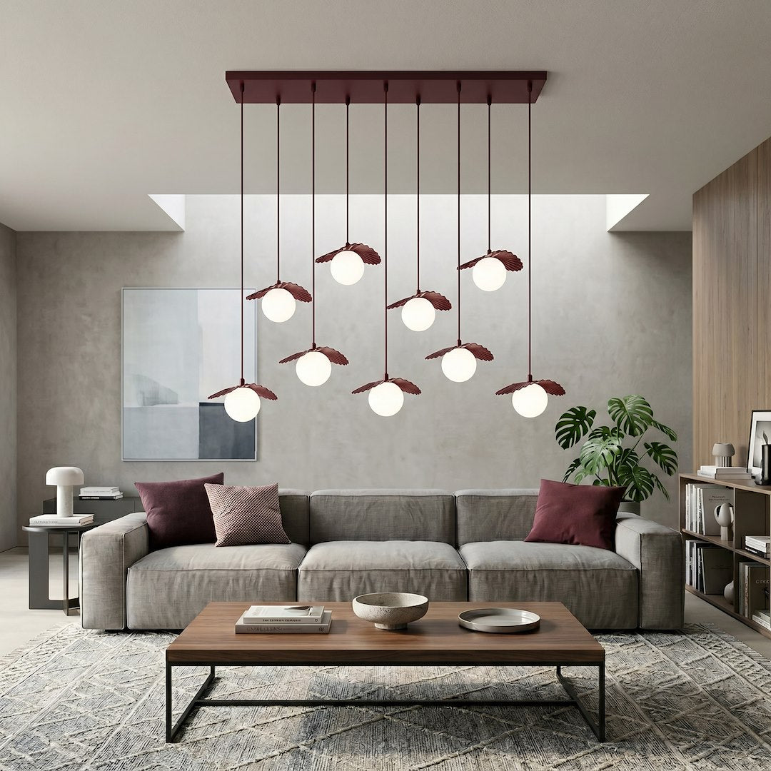 Mise en ambiance dans un salon contemporain avec canapé gris et suspension allumée.