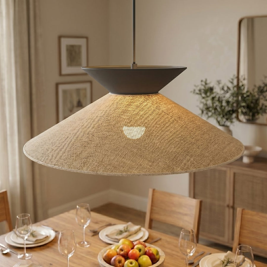 Gros plan sur l'abat-jour en rotin tressé diffusant une lumière chaude vers la table.