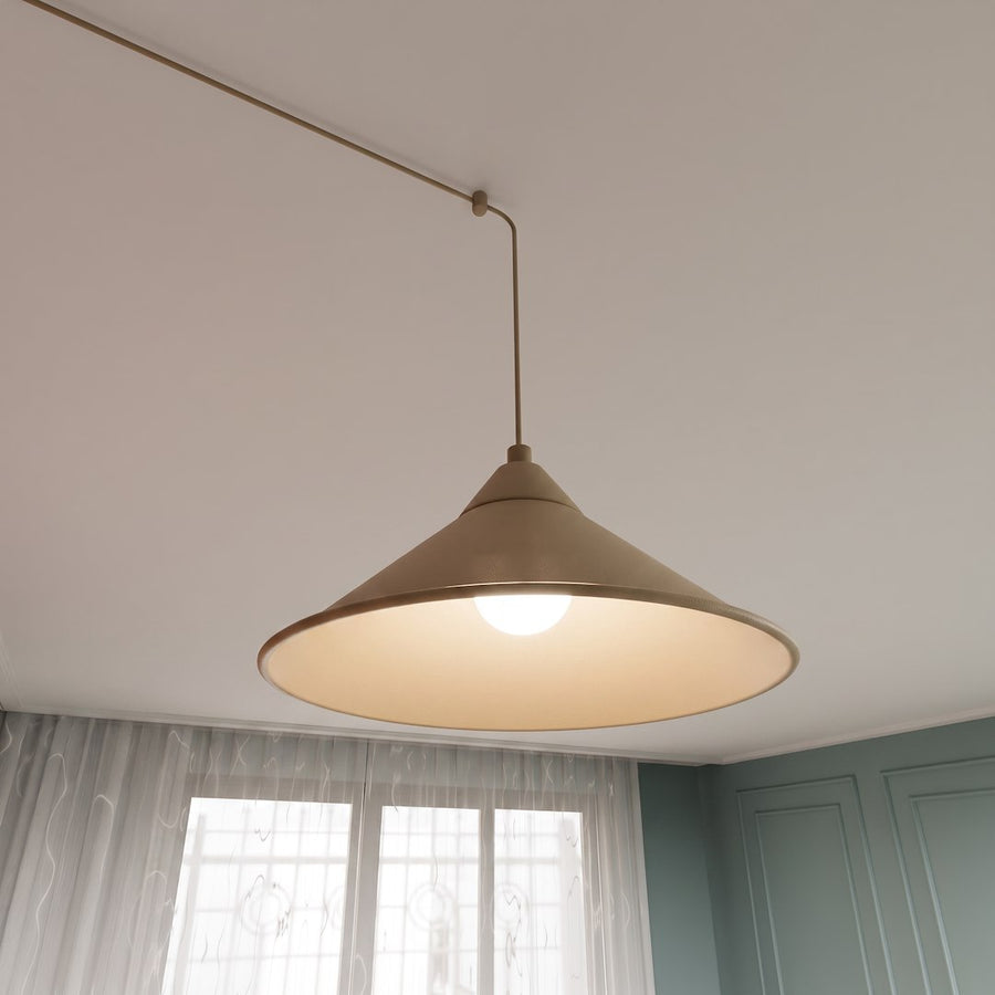 Détail d'un abat-jour conique beige allumé, câble fin et fixation au plafond.