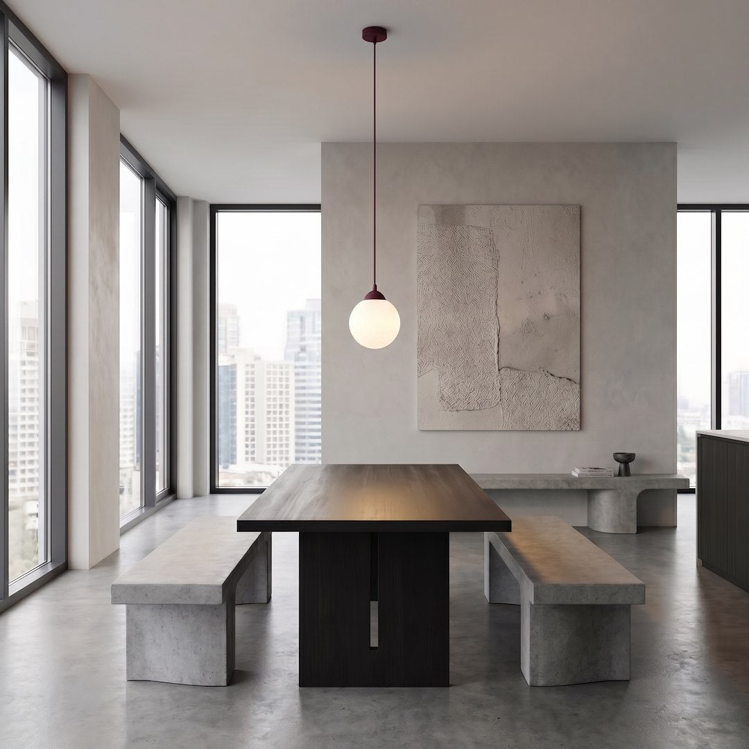 Grande pièce minimaliste, table sombre et bancs, suspension globe blanc au plafond