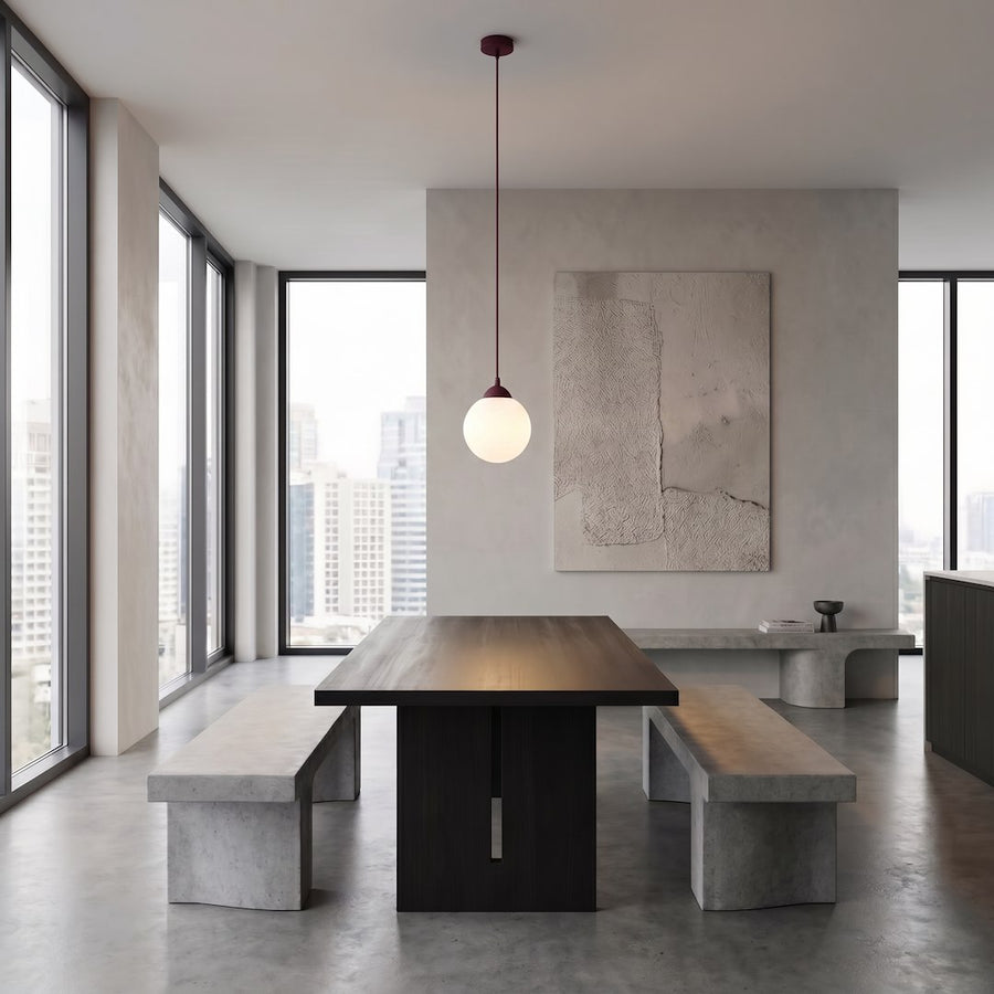 Grande pièce minimaliste, table sombre et bancs, suspension globe blanc au plafond