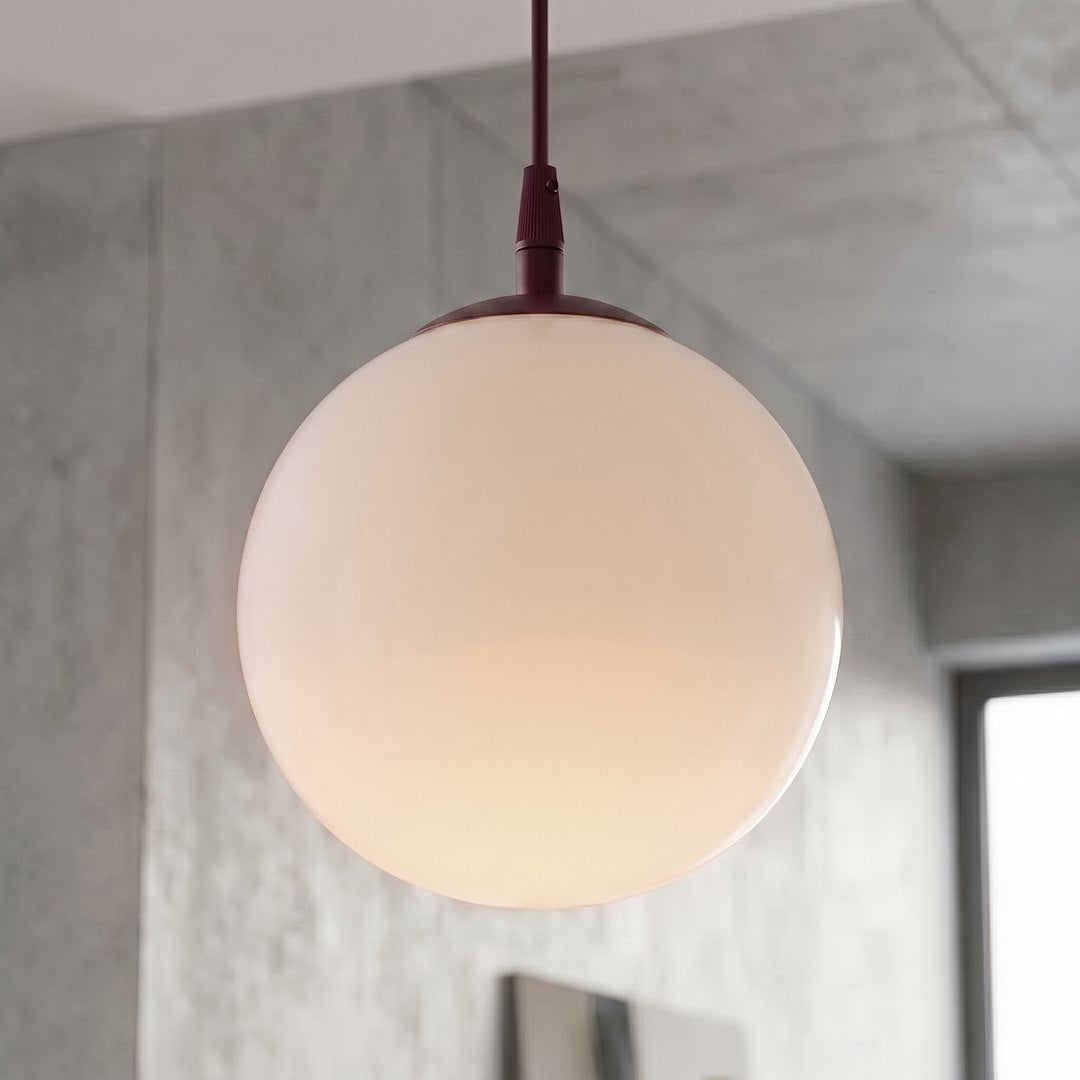 Gros plan sur le globe de verre opalin allumé et sa douille bordeaux