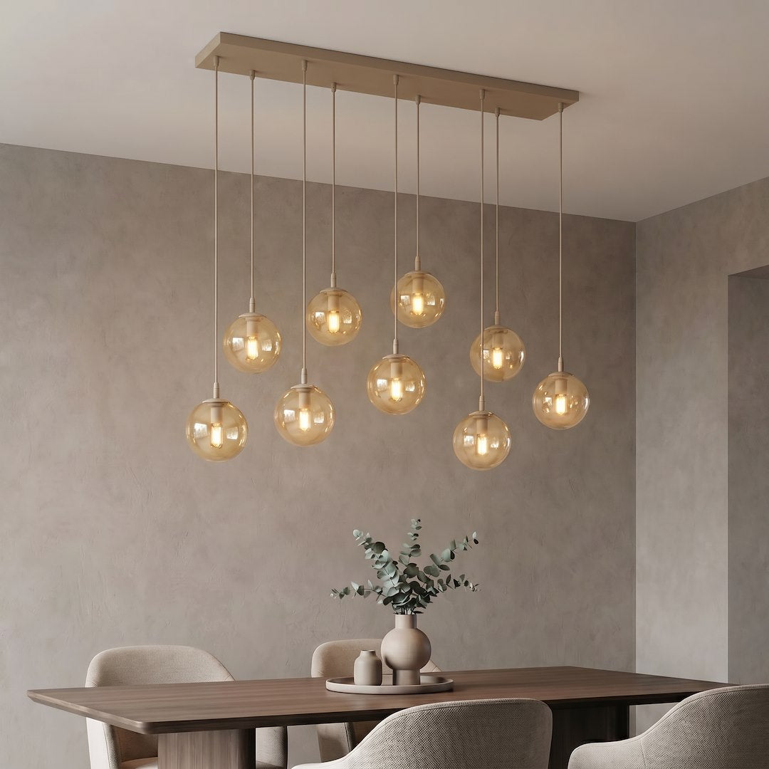 Suspension éclairée dans une salle à manger, vase d'eucalyptus sur table en bois foncé