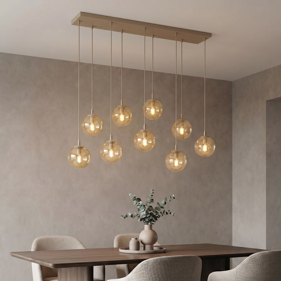 Suspension éclairée dans une salle à manger, vase d'eucalyptus sur table en bois foncé