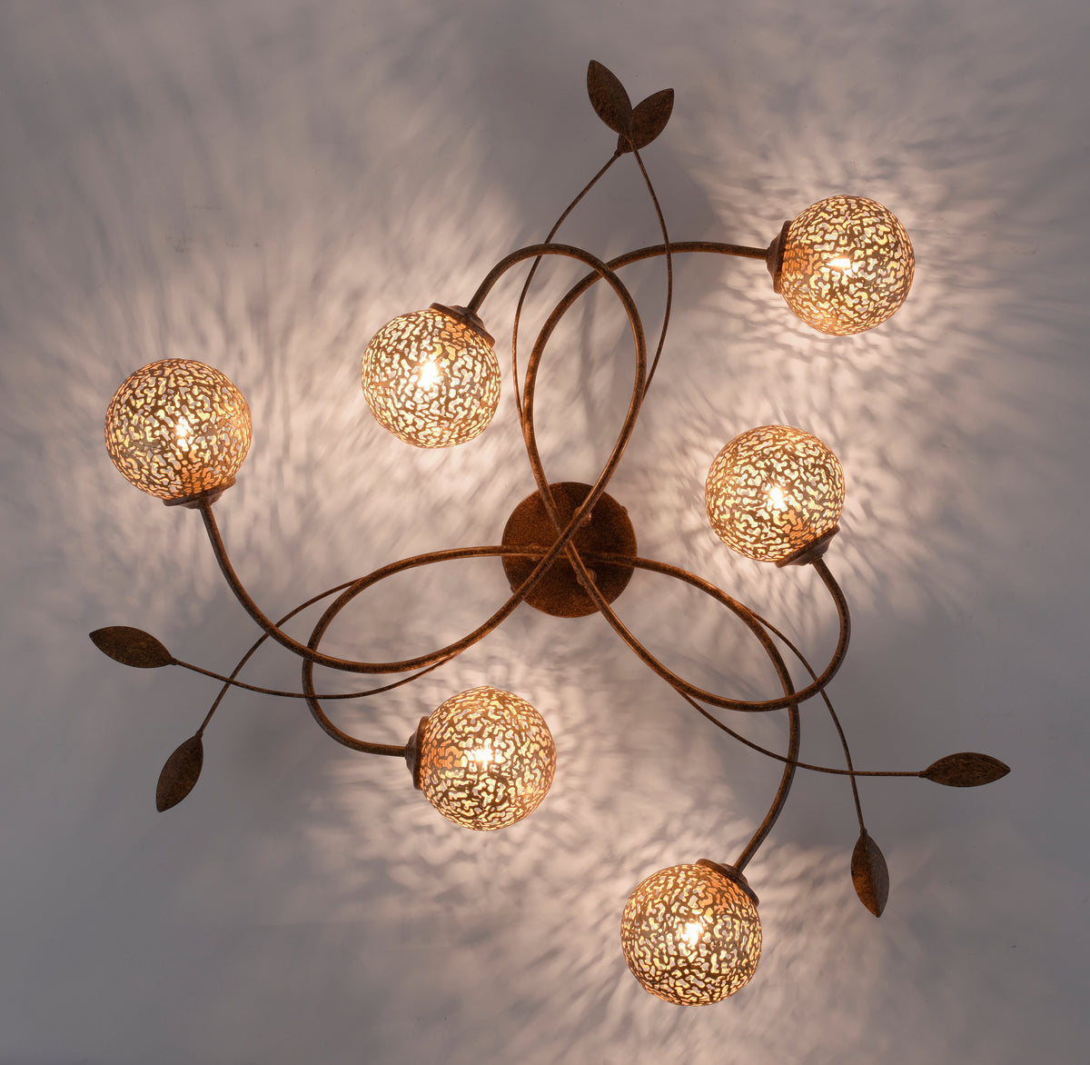 Vue en contre-plongée du plafonnier allumé, motifs lumineux projetés au plafond.