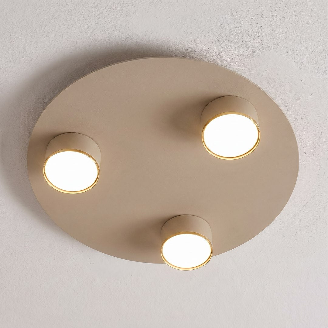 Plafonnier beige fixé au plafond, anneaux dorés autour des diffuseurs allumés
