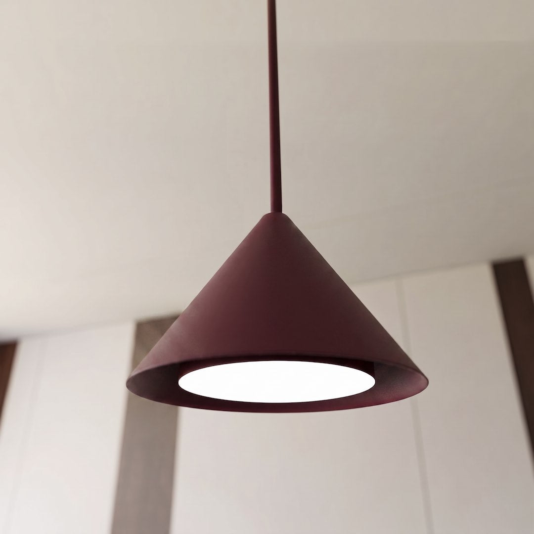 Gros plan sur un abat-jour conique bordeaux éclairé, montrant la finition mate et la lumière