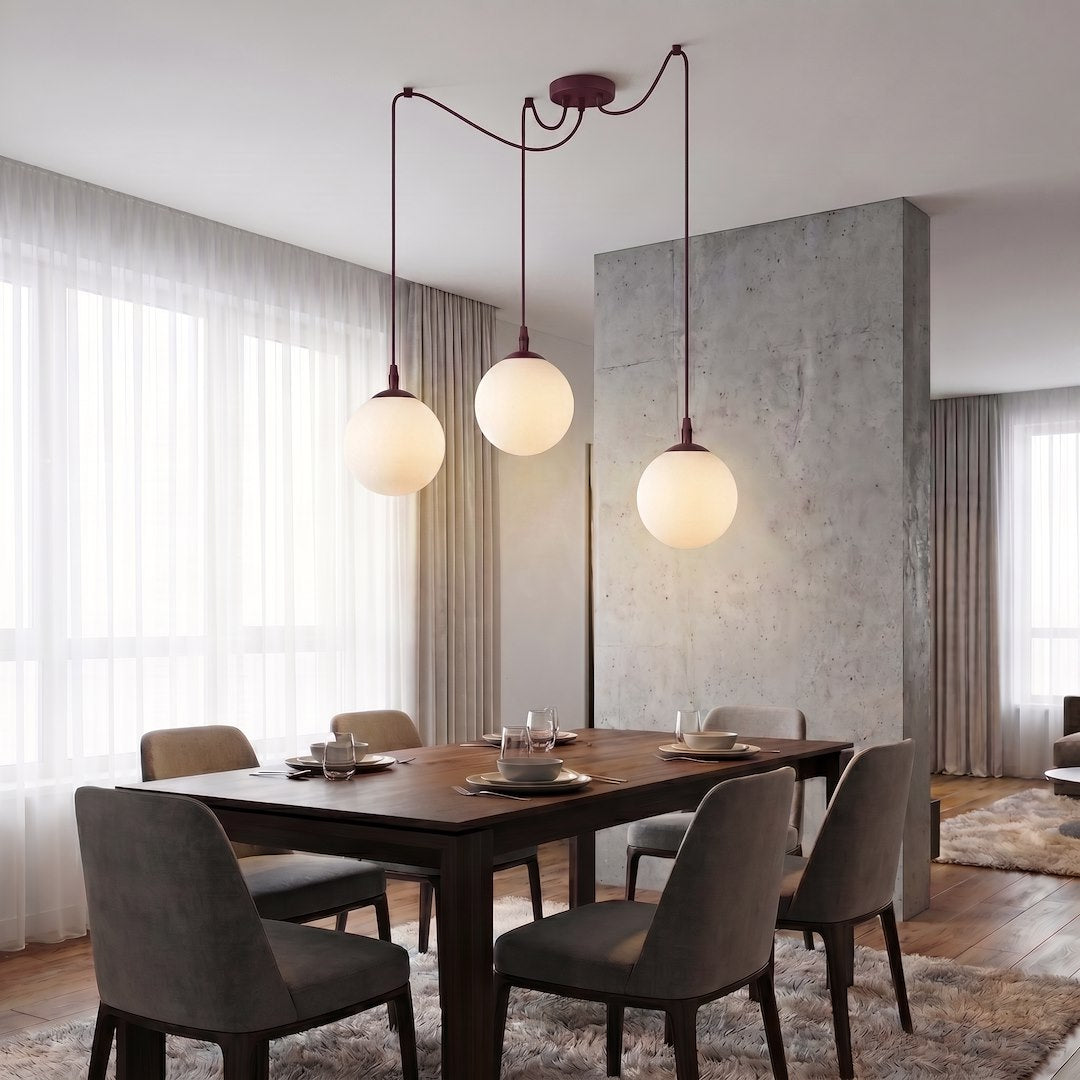 Mise en ambiance au-dessus d'une table à manger en bois, trois globes allumés