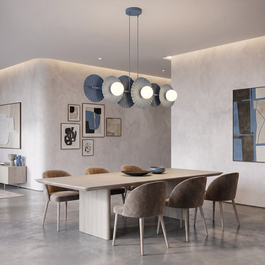 Suspension à six lumières au-dessus d'une table en bois, entourée de chaises et d'œuvres murales