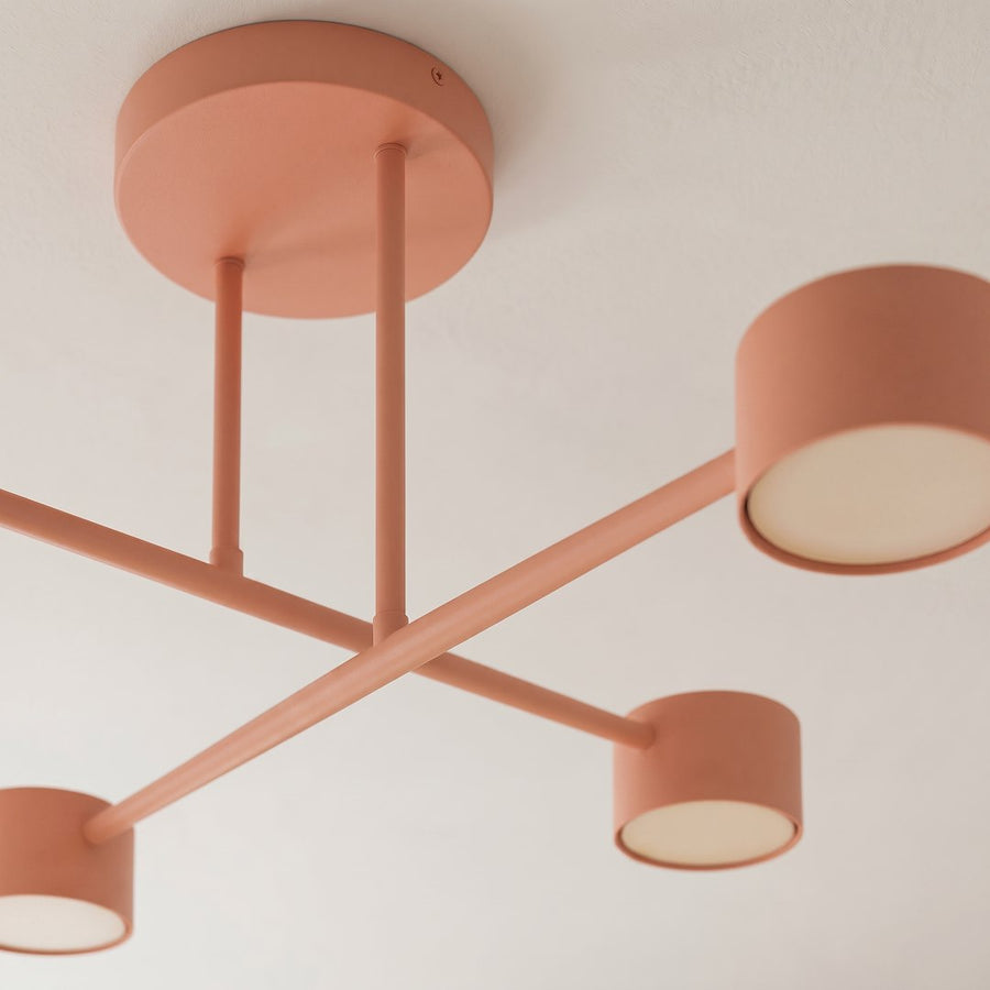 Détail rapproché des bras corail et des diffuseurs blancs des quatre lumières