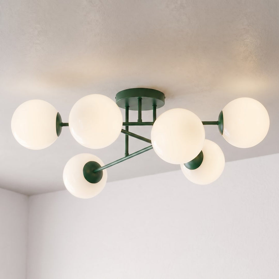 Gros plan du luminaire vert aux six globes lumineux, fixé au plafond d'une pièce claire.