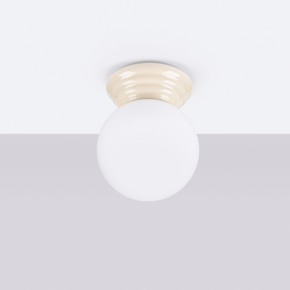 Plafonnier monté au plafond, éteint, globe blanc et base ivoire.