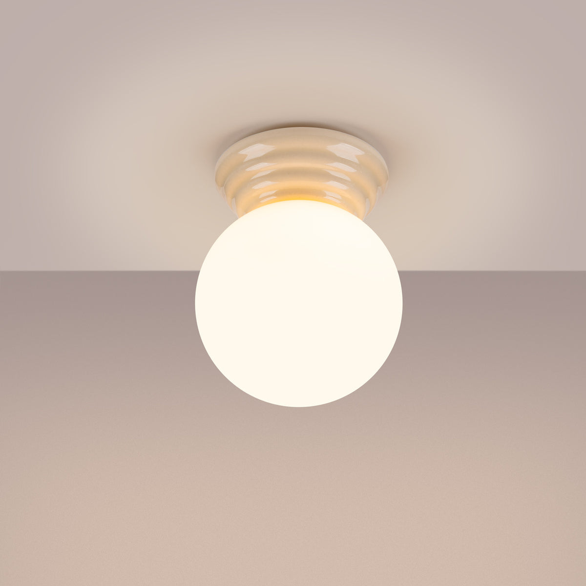 Plafonnier allumé au plafond, lumière chaude diffusée par le globe.