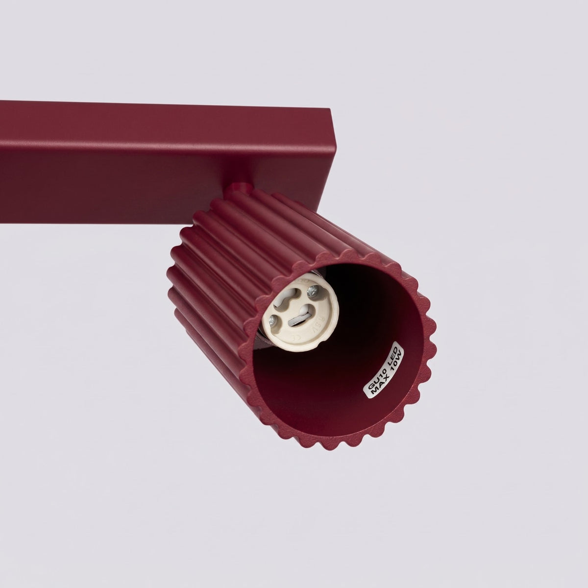 Détail de l'intérieur d'un spot bordeaux avec douille GU10 et étiquette 10W max.