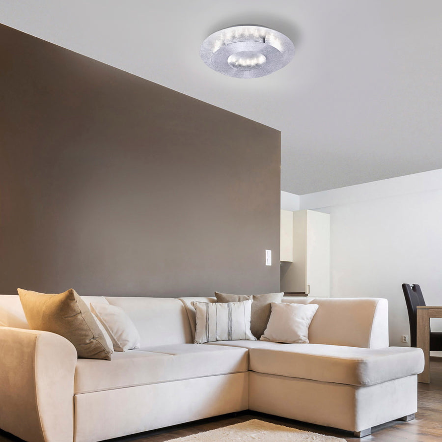 Plafonnier rond argenté fixé au plafond d'un salon contemporain avec canapé beige